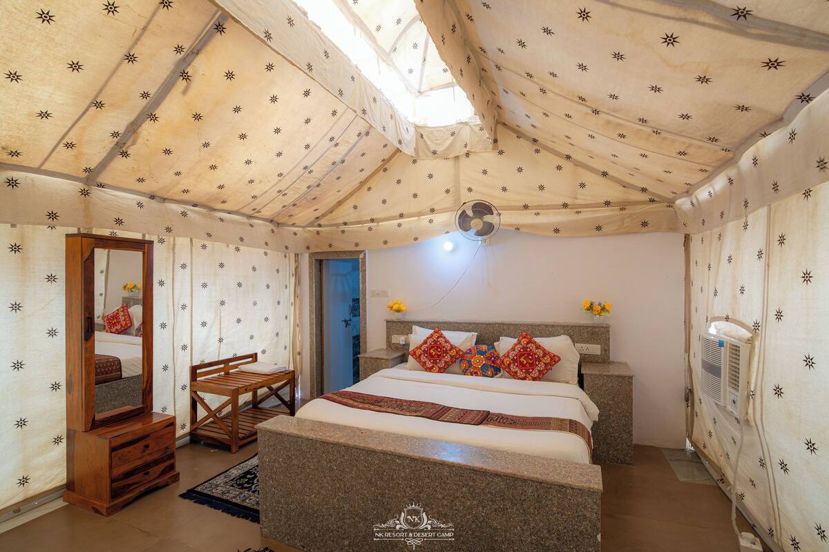 Une chambre à coucher avec un lit, une chaise en bois, un miroir et un ventilateur de plafond.