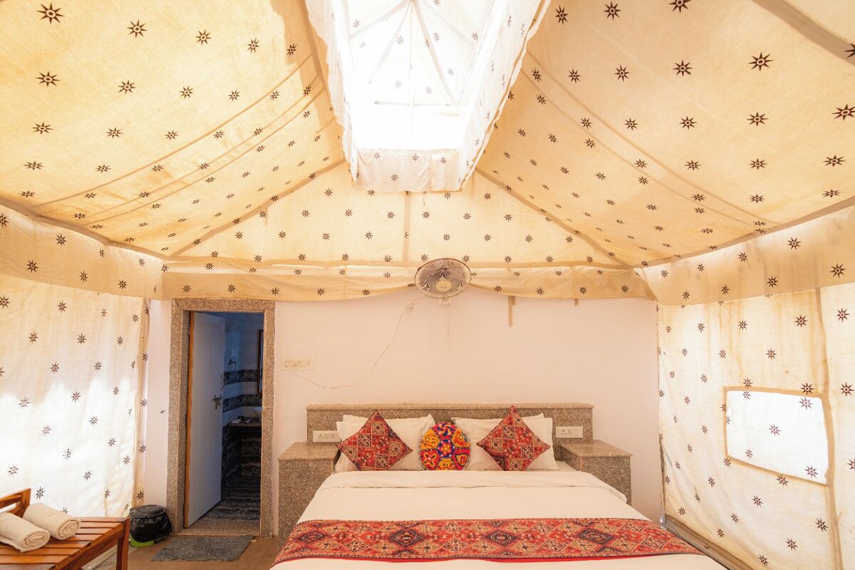 Una habitación con una cama, una silla de madera y un ventilador.