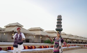 Un hombre y una mujer con vestimenta tradicional realizando una acrobacia, equilibrando una olla decorada en sus cabezas.