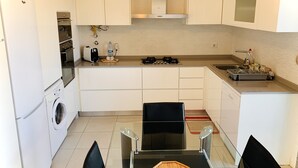 Una cocina compacta equipada con lavadora, cafetera y estufa a gas.