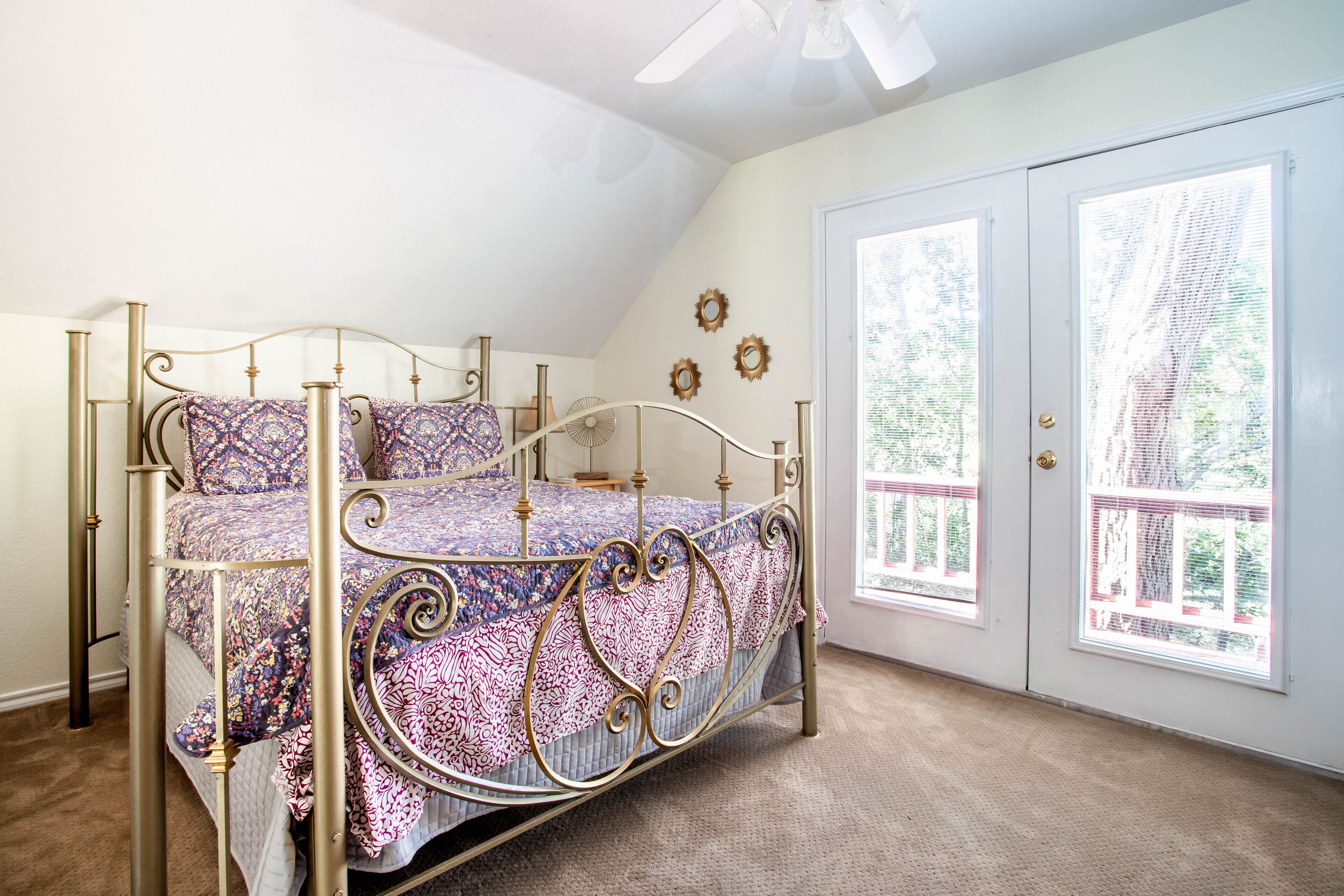 A bedroom with a four-poster bed, a ceiling fan, and a view of the outdoors through a door with frosted glass.