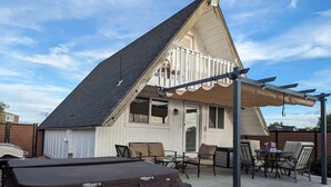 Et hus med overdækket terrasse, udendørs møbler og et spabad.