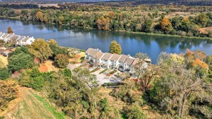 A residential area with houses near a lake, surrounded by trees and greenery.