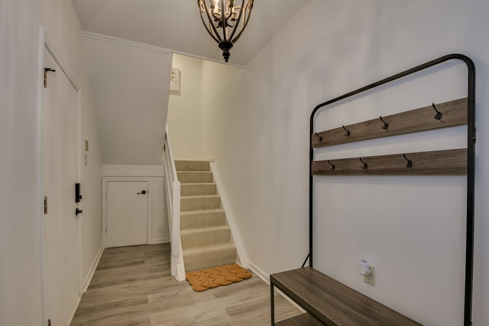 A hallway with a wooden bench, a wall-mounted rack, and a staircase.