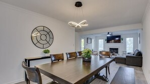 A spacious dining area with a long wooden table, several chairs, and a modern pendant light.
