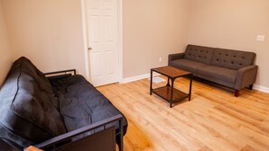 Ein Wohnzimmer mit einer schwarzen Couch, einer braunen Couch und einem kleinen Tisch.