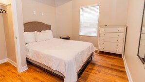 Ein Schlafzimmer mit Bett, Schminktisch, Nachttisch und Fenster.