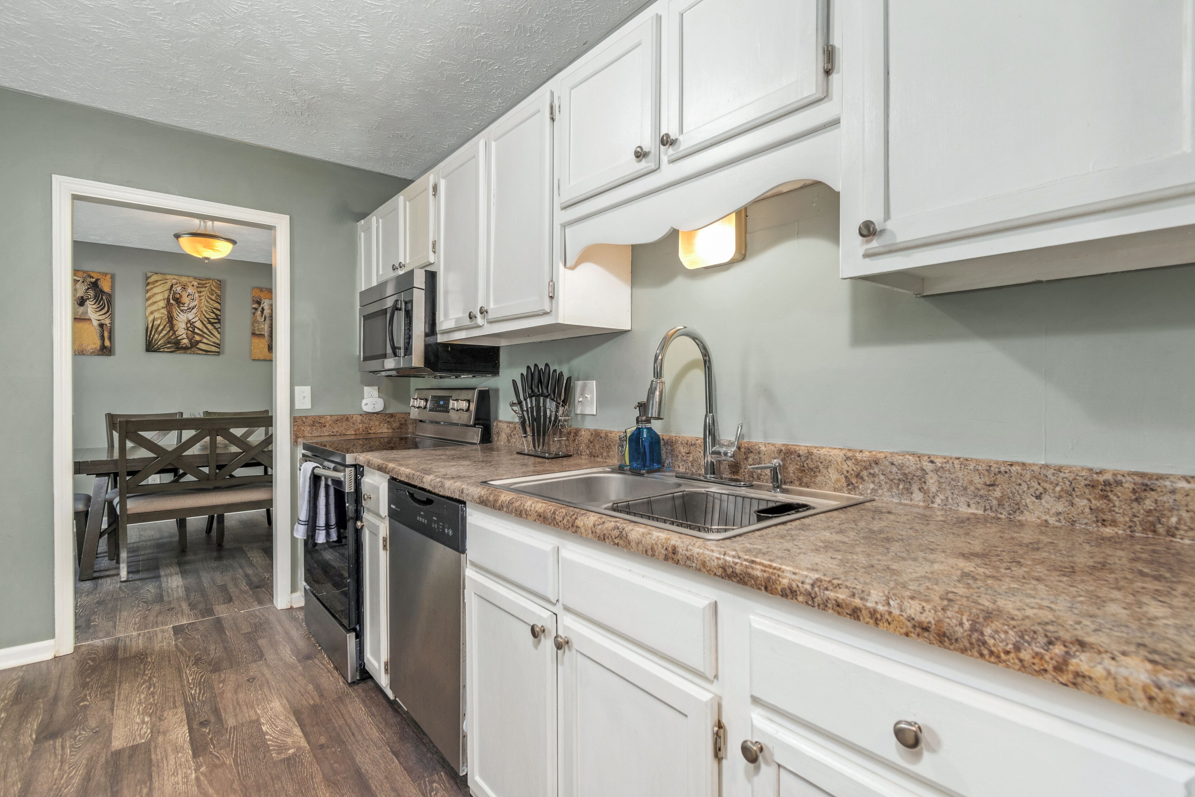 A kitchen with white cabinets, granite countertops, a dishwasher, and a microwave.