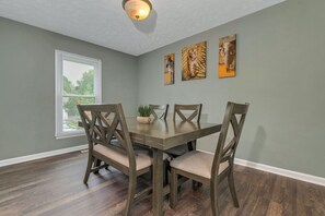A dining room with a rectangular table, six chairs, and two wall-mounted paintings of animals. - Spacious home near the heart of Fayetteville, NC!! (Fayetteville)