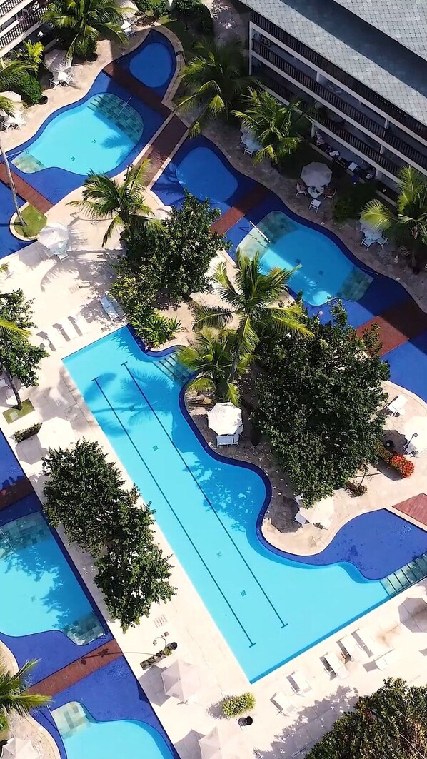 A resort with multiple swimming pools, palm trees, and lounge areas. - Flat Luxo Térreo Nannai Residence (Ipojuca)