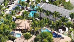A resort with multiple swimming pools surrounded by palm trees and modern buildings. - Flat Luxo Térreo Nannai Residence (Ipojuca)