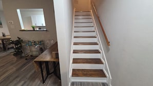 A staircase with wooden steps and a wooden handrail leading to an upper floor.