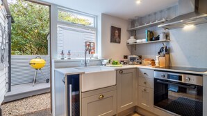 Een moderne keuken met een inbouwoven, een spoelbak en een raam met uitzicht op een tuin.