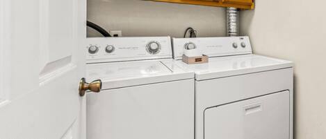 A white washer and dryer unit with wooden cabinets above.