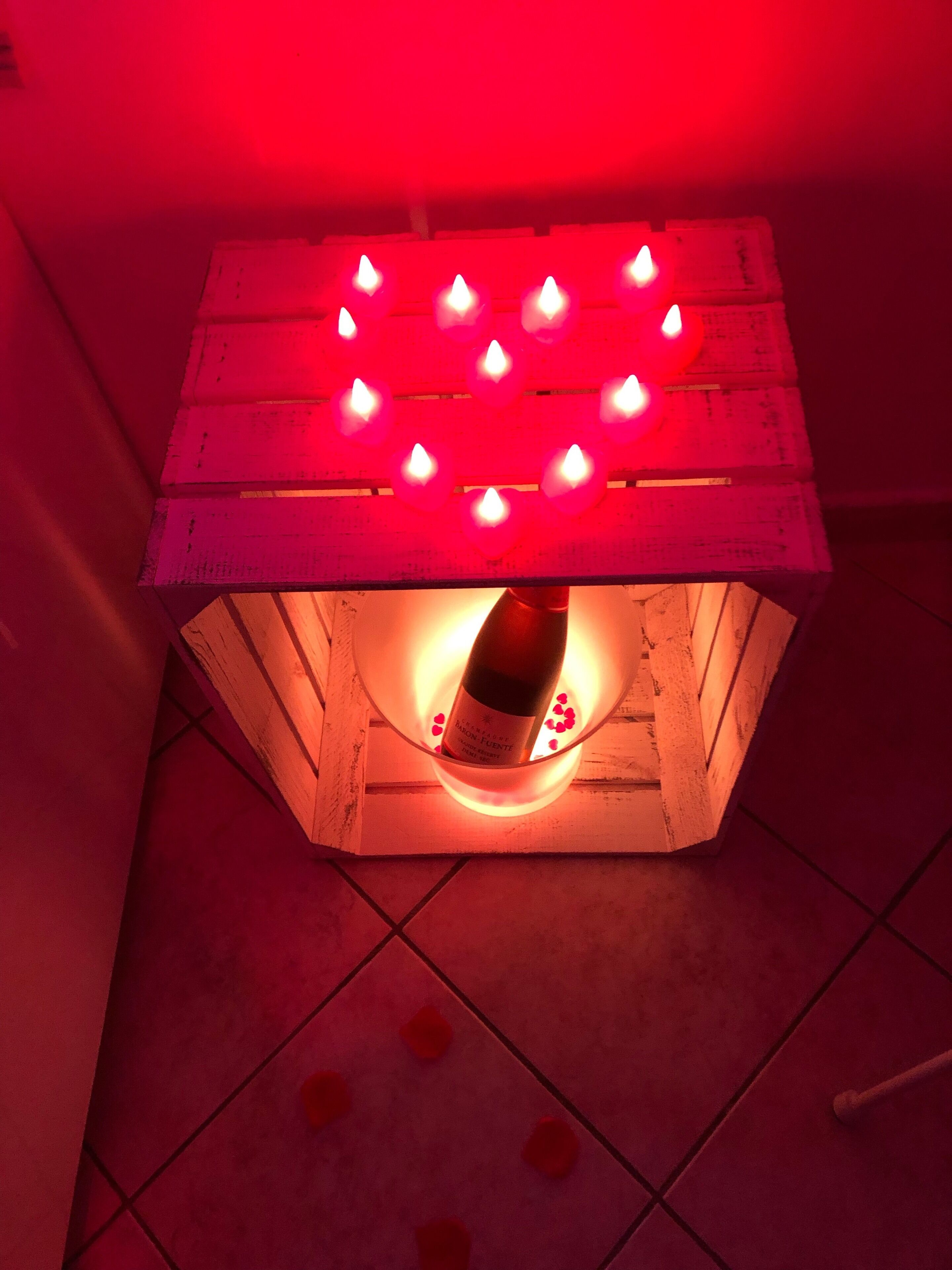 A wooden crate with a bottle of wine and heart-shaped lights on top.