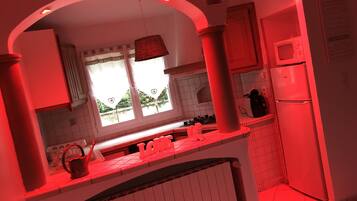 A kitchen with a window, a refrigerator, and a sink.