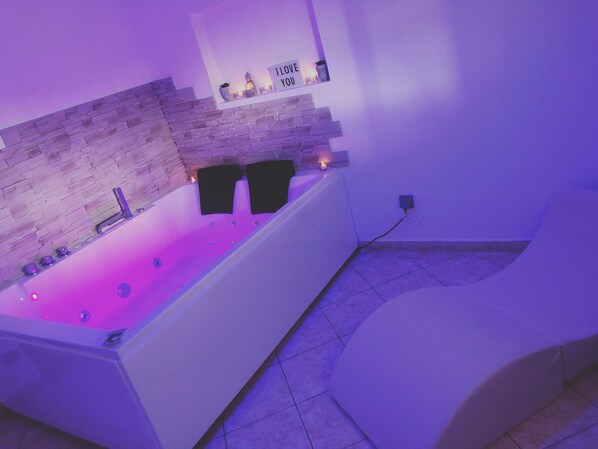 A modern bathroom with a stone wall, a bathtub, and a sign that says "I love you." - Spa house with private Jacuzzi and whirlpool bath overlooking the countryside (Saint-Genest-Lerpt)