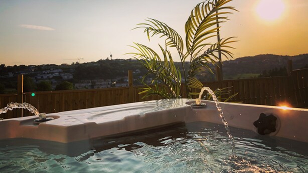 Ein Whirlpool mit Wasserfall und Blick auf eine Wohngegend im Abendrot.