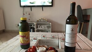 Ein Holztisch mit einer Dago-Flasche, einer Weinflasche sowie Schalen mit Obst und Nüssen.