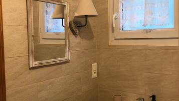 Un baño con lavamanos, espejo y cortinas decorativas.