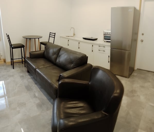 A modern kitchen with a sofa, a dining table, and chairs. - Sandwich Boutique Hotel (Windsor)