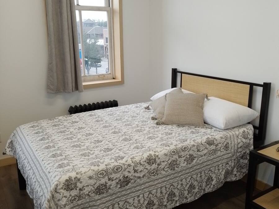 Une chambre à coucher avec un lit, une fenêtre, un radiateur et une chaise.
