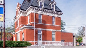 A red brick building with a gabled roof and white trim, featuring a post office and a sign for a tea shop. - Sandwich Boutique Hotel (Windsor)