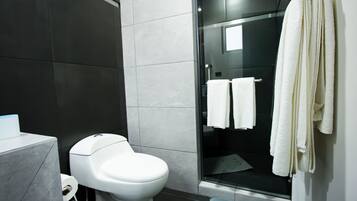 Ein modernes Badezimmer mit Toilette, einer Duschkabine aus Glas und einem Handtuchhalter.