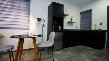 A modern kitchen with a dining area, including a table, chairs, and a refrigerator.
