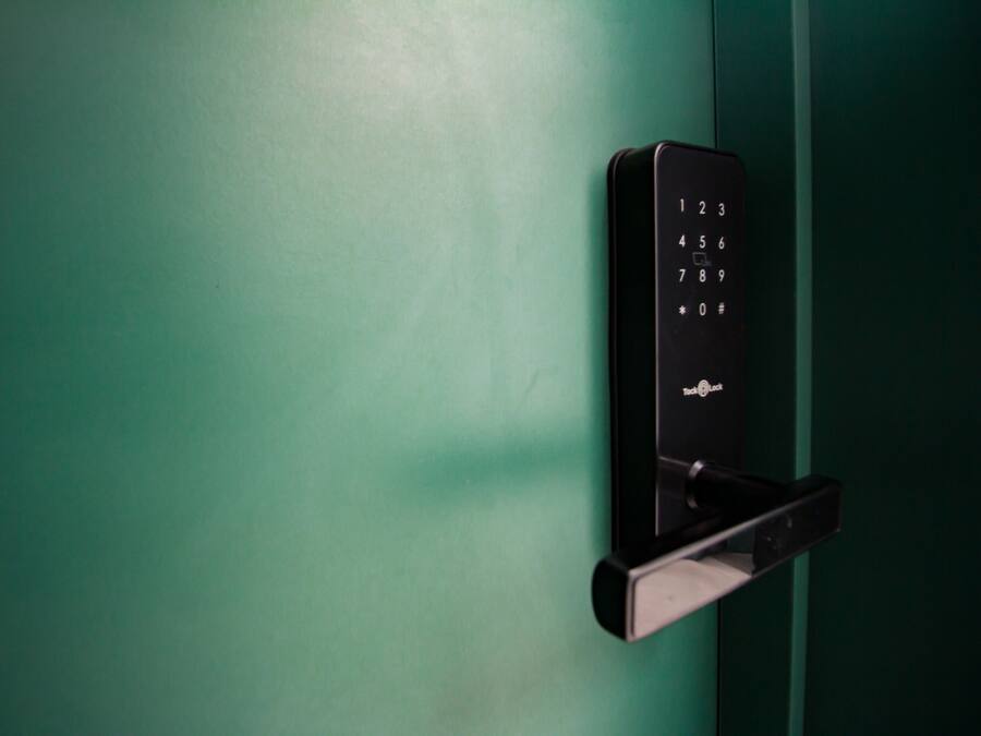 Un panel táctil electrónico negro instalado en una puerta verde.
