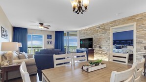 A spacious living room with a dining area, a TV, and a balcony with a view. - Lake & Golf View 3 bedroom Condo 1516 with Resort access and short walk to beach (North Myrtle Beach)