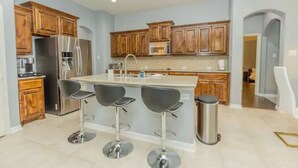 Una cocina moderna con armarios de madera, electrodomésticos de acero inoxidable y una isla central con taburetes de bar.
