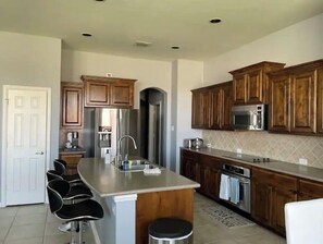 A kitchen with wooden cabinets, stainless steel appliances, and a central island with bar stools.