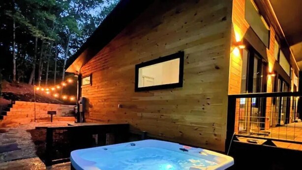 A wooden cabin with a hot tub, outdoor seating, and string lights. - Modern Mountain Getaway with hot tub & fire pit 10 minutes to Helen (White County)
