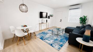 Una sala moderna con sofá, mesa de centro y comedor con sillas.