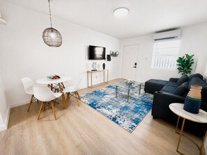 Un salon moderne comprenant un canapé, une table basse et un coin repas avec des chaises.