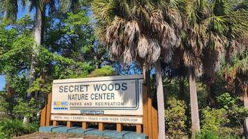 Señal para el Centro de la Naturaleza Secret Woods con una lista de servicios que incluye salón de alquiler, exhibiciones, senderos y un nuevo mirador del río.