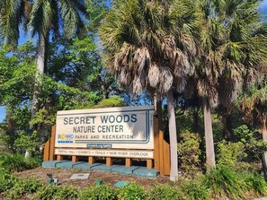 Une pancarte indiquant le centre d’interprétation de la nature de Secret Woods, avec une liste des installations disponibles, notamment une salle de location, des expositions, des sentiers et un nouveau point de vue sur la rivière.