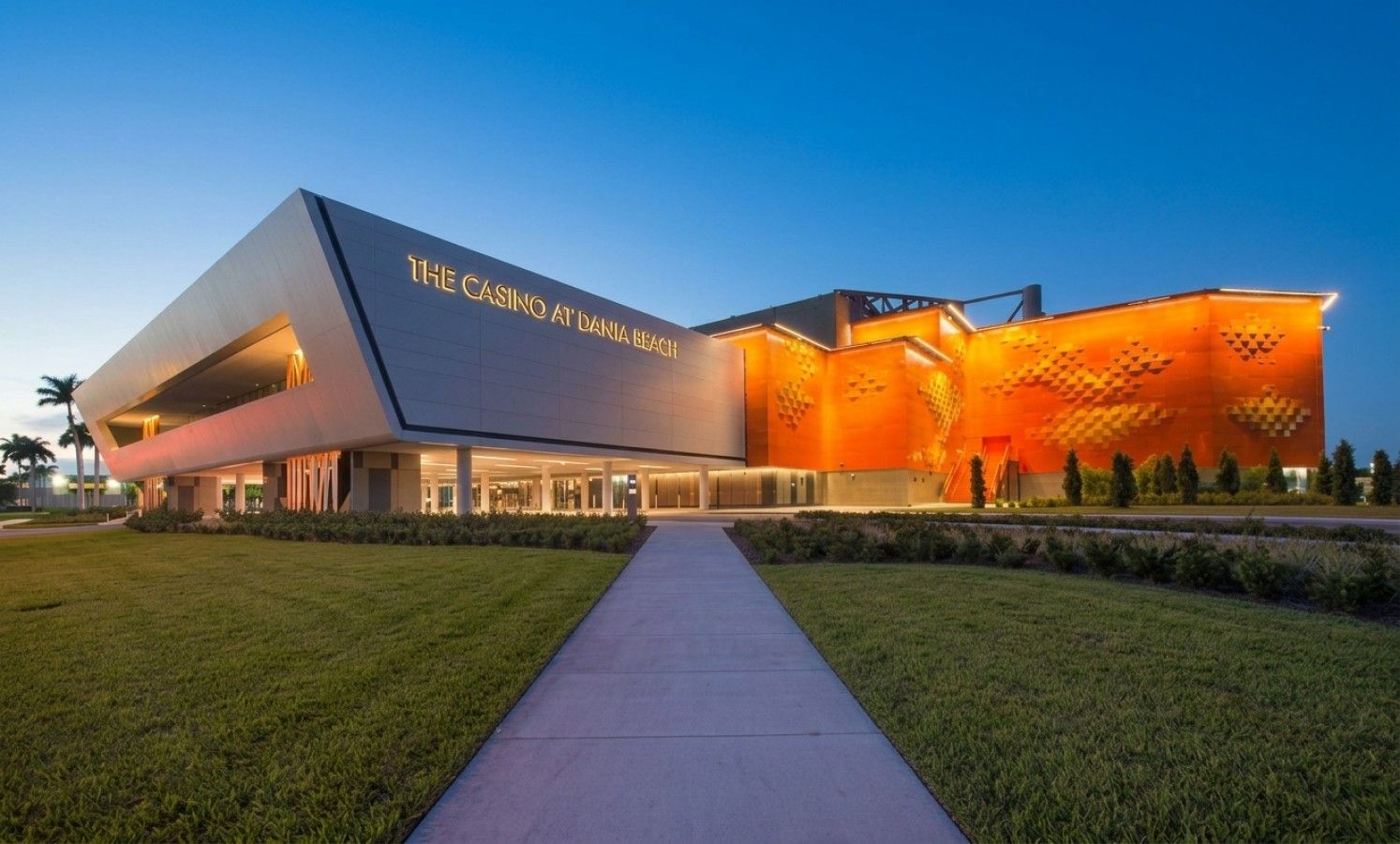 A modern building with a prominent entrance and a large, illuminated sign reading 'The Casino at Dania Beach'.