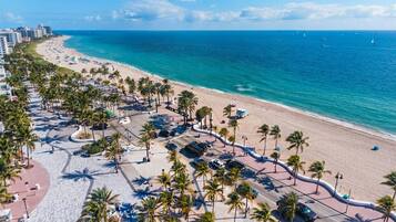 Zona costera con playa, palmeras y una carretera que conduce a la playa.