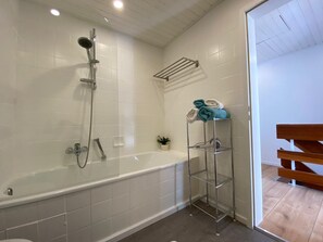 Een bad/douchecombinatie, een haardroger, handdoeken, zeep