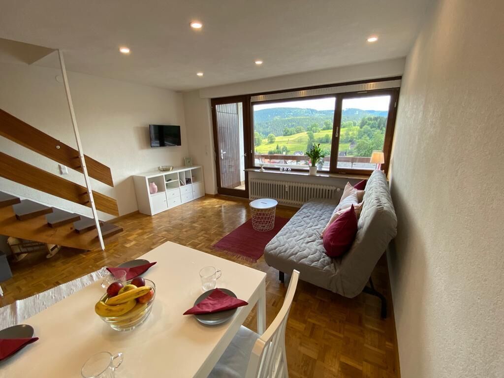 Un soggiorno moderno con zona pranzo, divano, televisione e vista sulla campagna.