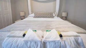 A neatly made bed with a white canopy, two bedside lamps, and a set of towels on the bed. - Super Clean Fantastic Pool Home Near Everything (Orange Park)
