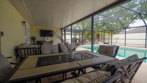 A covered patio area with a pool, a dining table with chairs, and a sofa. - Super Clean Fantastic Pool Home Near Everything (Orange Park)