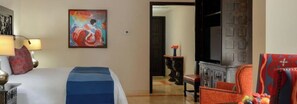 Habitación de hotel con cama, un cuadro, chimenea y vistas al pasillo.