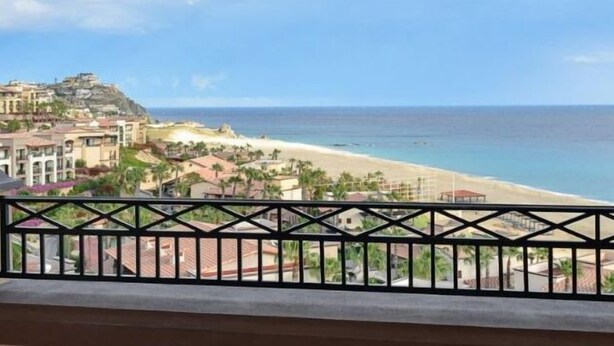 Un balcón con vista a la playa y edificios.