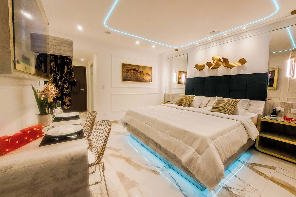A modern bedroom with a large bed, a desk, and a chair.