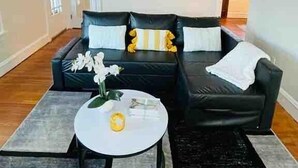 Un salon avec un canapé noir, une table basse et un élément décoratif mural.