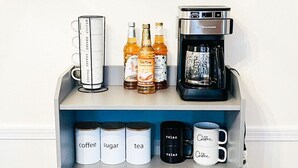 Un comptoir de cuisine avec une machine à café, du sucre, du thé et des tasses à café.