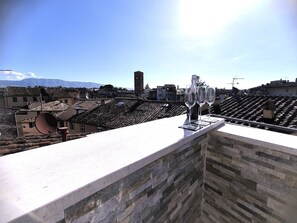 Una terraza en la azotea con un muro de piedra, una antena parabólica grande y tres copas de vino vacías.